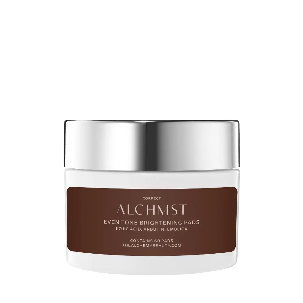 A white container labeled "Alchmst Even Tone Brightening Pads" with a metallic silver lid against a white background. Contains kojic acid, arbutin, and emblica.