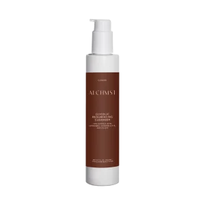 A bottle of Alchemist Glycolic Resurfacing Cleanser with white pump and brown label, containing glycolic acid, vitamins, and Co-Q10 for skincare.
